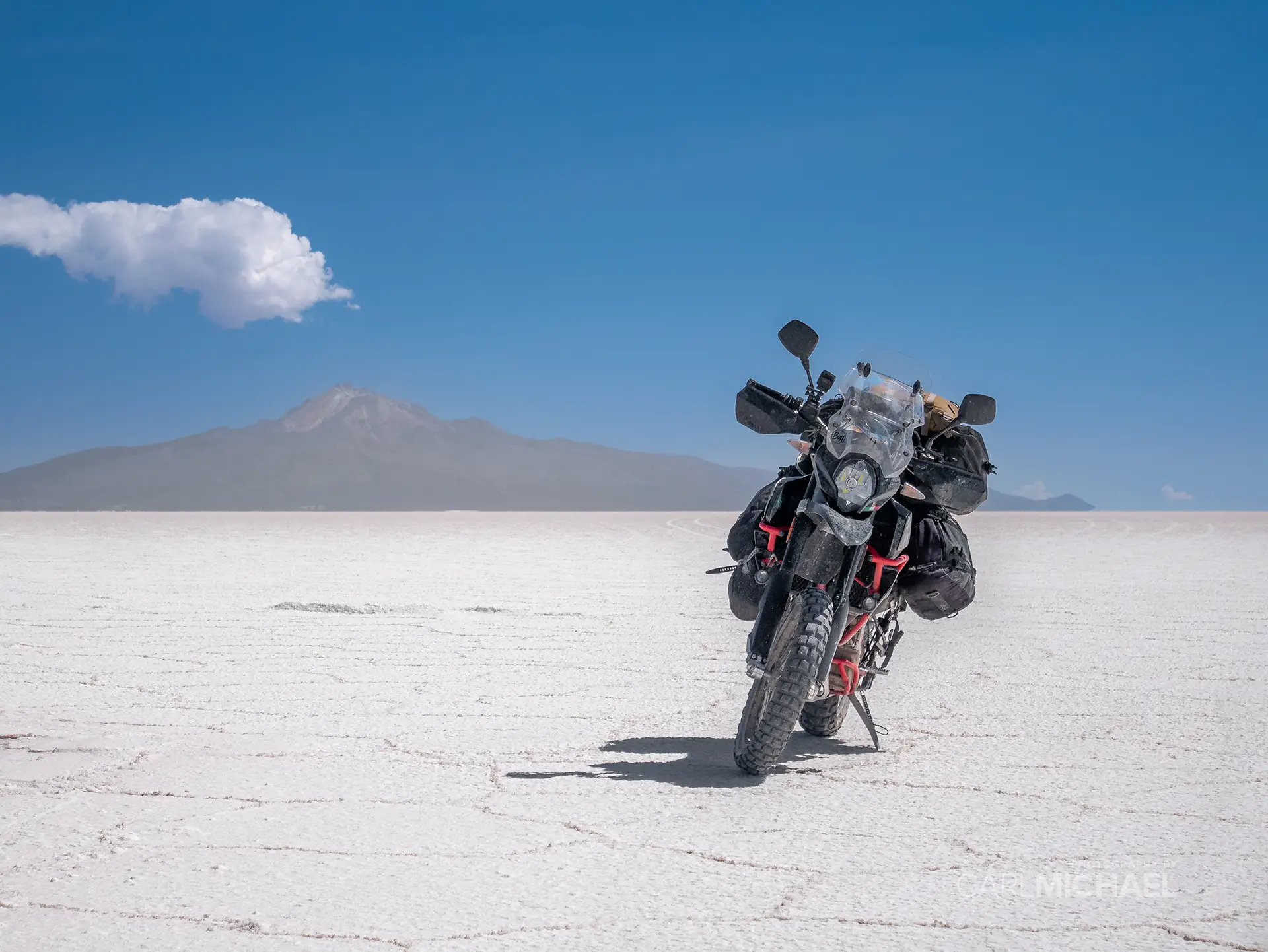 SWM Superdual T motorcycle on the Salar de Uyuni, Bolivia. There is a volcano in the background